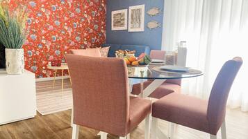 Enjoy meals in this stylish dining area with a glass table, comfortable chairs, and vibrant decor.