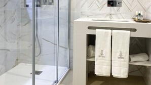 A modern bathroom with a glass-enclosed shower, a vanity with a mirror, and two towels hanging on the wall.