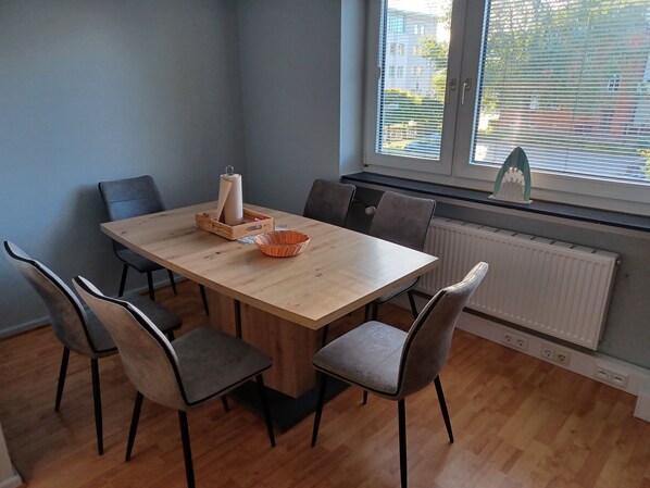 A dining area with a wooden table, six chairs, a basket, and a towel dispenser.