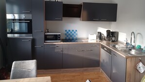 Cocina compacta con gabinetes oscuros, microondas, tostadora y cafetera.