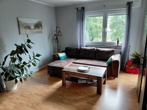 A living room with a sofa, a coffee table, and a window with curtains.