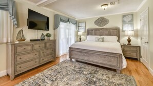 Un dormitorio con una cama grande, un aparador, un televisor y un adorno de pared.
