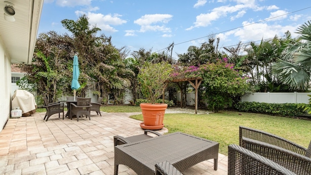 Un patio exterior con mobiliario de mimbre, una mesa cubierta y una planta en maceta.