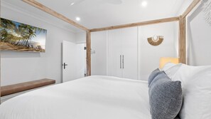 Un dormitorio con una cama grande, un banco, una puerta y un adorno en la pared.