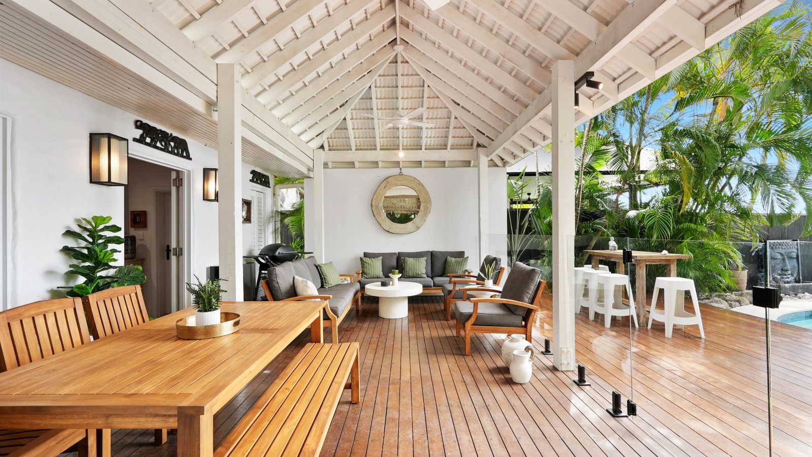 Un espace extérieur abrité, doté d’une terrasse en bois, de coins salon et offrant une vue sur la verdure environnante.