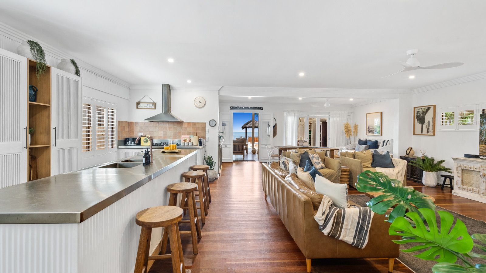 Une cuisine moderne dotée d’un îlot central, de tabourets en bois, d’une banquette intégrée et offrant une vue sur l’extérieur.
