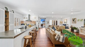 Une cuisine moderne dotée d’un îlot central, de tabourets en bois, d’une banquette intégrée et offrant une vue sur l’extérieur.