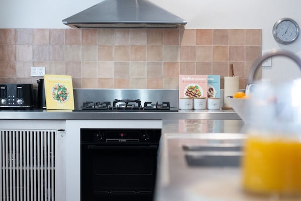 A kitchen with a Bosch gas stove, a dishwasher, and a clock on the wall.