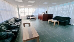 Una sala moderna con un sofá de cuero, una mesa de centro de madera, un sofá verde oscuro y una pequeña mesa de madera.