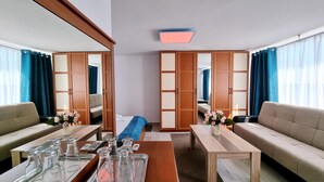 A hotel room with a sofa, a coffee table, a bed, and a wardrobe. - Hotel Capitol Eforie Sud (Eforie)