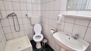 Un baño pequeño y limpio con inodoro, lavabo y ducha.