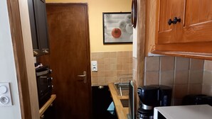 Una cocina compacta con microondas, cafetera y estufa.