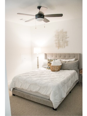 Restful retreat with a ceiling fan, comfortable bed, and woven basket.