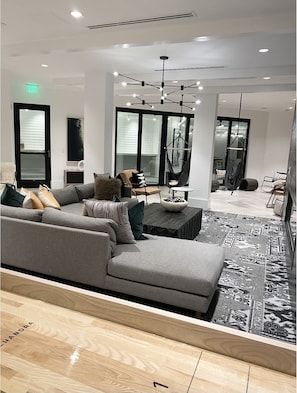 Relax in a spacious living area with a large sofa, coffee table, and patterned rug, offering a view of the outdoors.