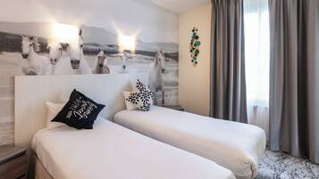 A hotel room with two beds, a wall mural of horses, a nightstand, and a window with curtains.