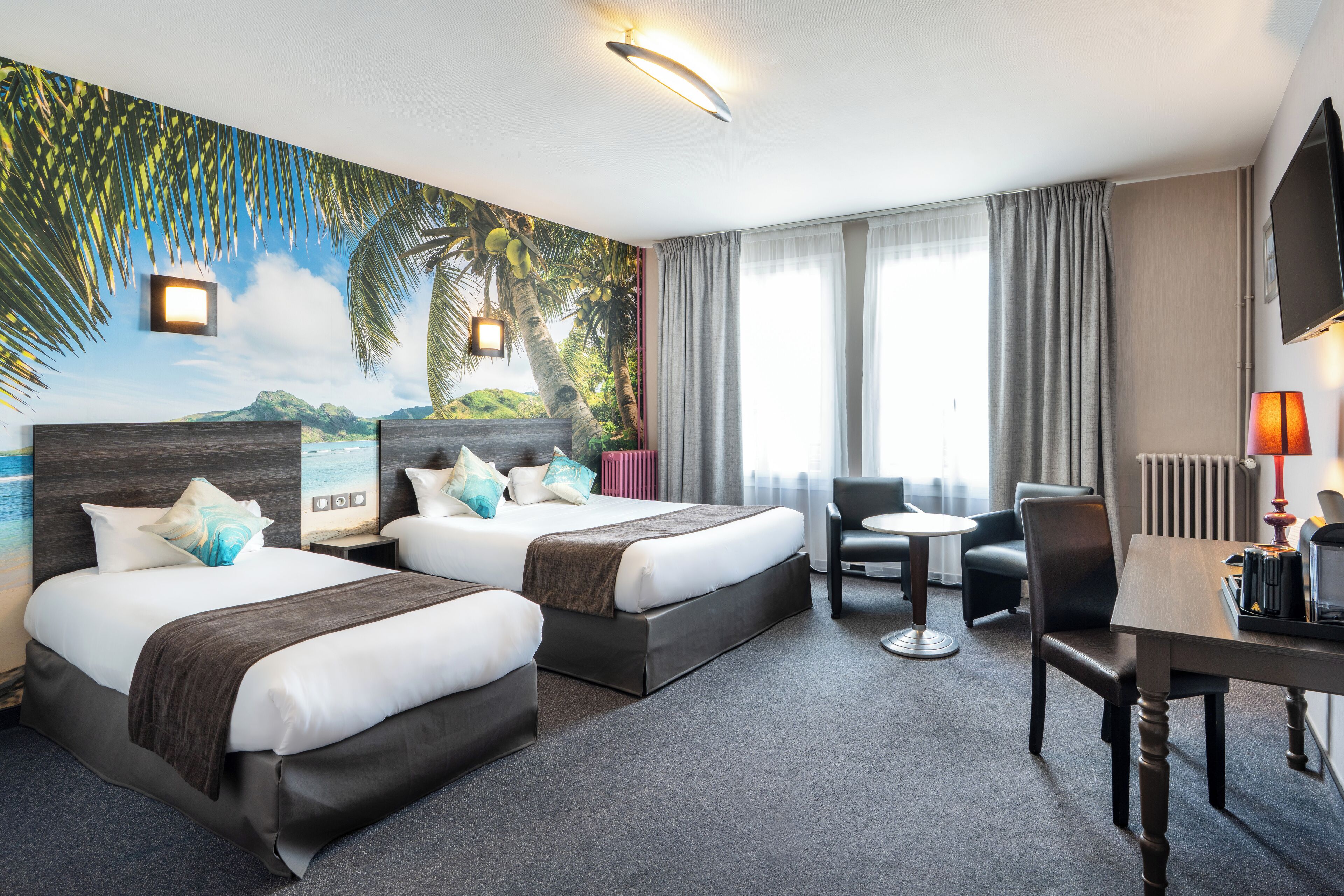 Une chambre d’hôtel avec deux lits, un bureau, une chaise, une petite table, un téléviseur et une fresque représentant un paysage tropical.