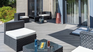 An outdoor patio area with seating, a table, and a large umbrella. - Logis Hotel des Ducs (Alencon)