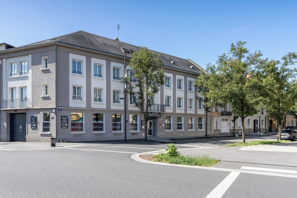 A multi-story hotel with a neutral facade, large windows, and a visible entrance.
