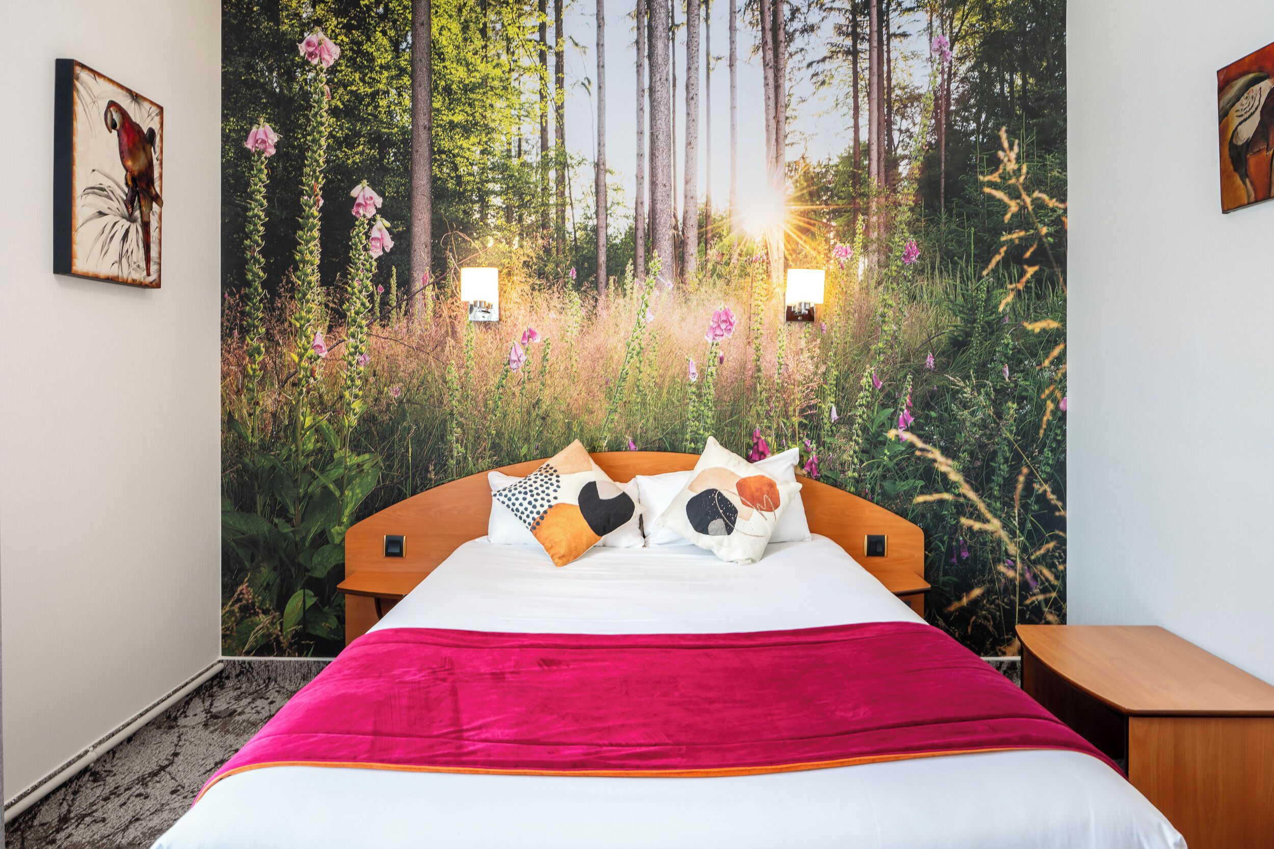 A bedroom with a bed, a nightstand, a wall-mounted lamp, and a painting.