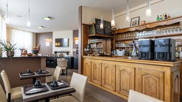 Um restaurante com balcões de bar em madeira, luminárias pendentes e diversos copos expostos em prateleiras.