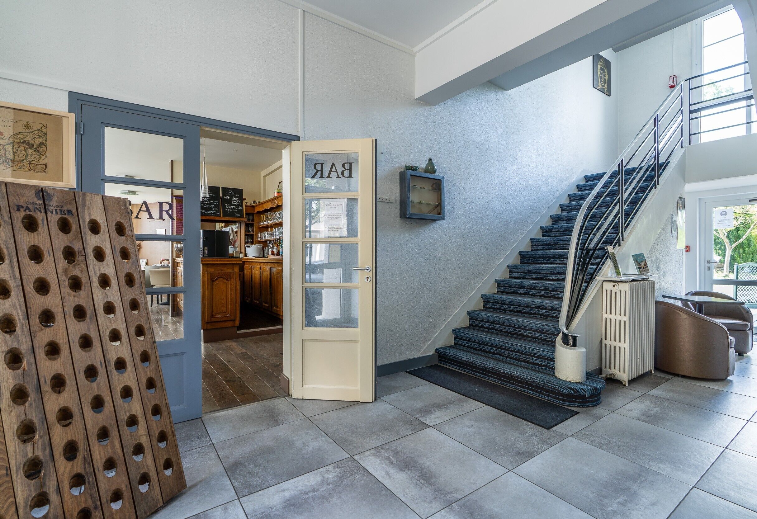 A modern interior with a staircase, a wooden door with a sign, and a view into a kitchen area.