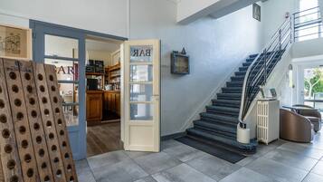 Un interior moderno con una escalera, una puerta de madera con un letrero y vistas a una zona de cocina.