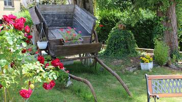 A garden with a wooden cart, red roses, and a bench.