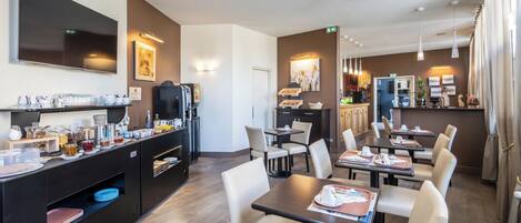 A modern hotel lobby with a coffee station, seating area, and a reception desk.