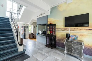 Um lobby moderno com escada, balcão de recepção, TV na parede e um armário decorativo.