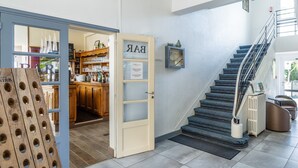 A modern interior with a staircase, a bar area, and a wooden structure with holes. - Logis Hotel des Ducs (Alencon)