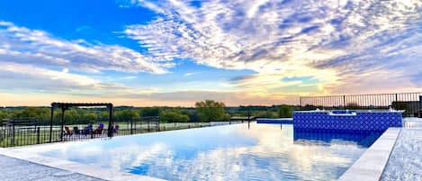 Una piscina con una pérgola y sillas de descanso, rodeada por una cerca.