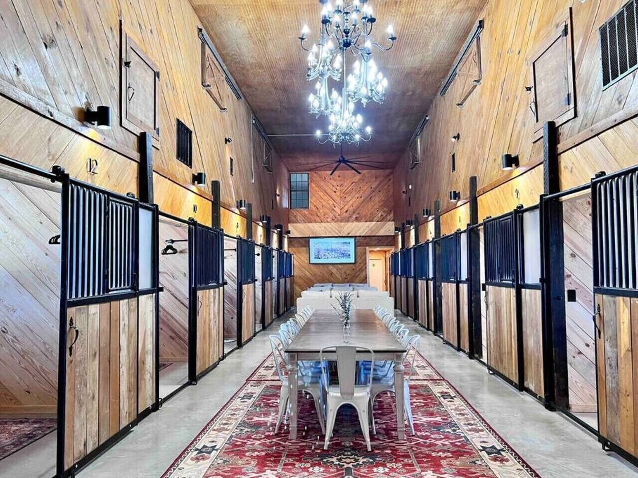 A long, narrow room with a central table and chairs, wooden walls, and a chandelier.