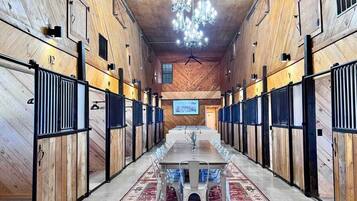 A long, narrow room with a central table and chairs, wooden walls, and a chandelier.