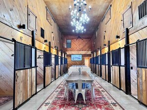 Um espaço comprido e estreito com uma mesa central e cadeiras, paredes de madeira e um candelabro.