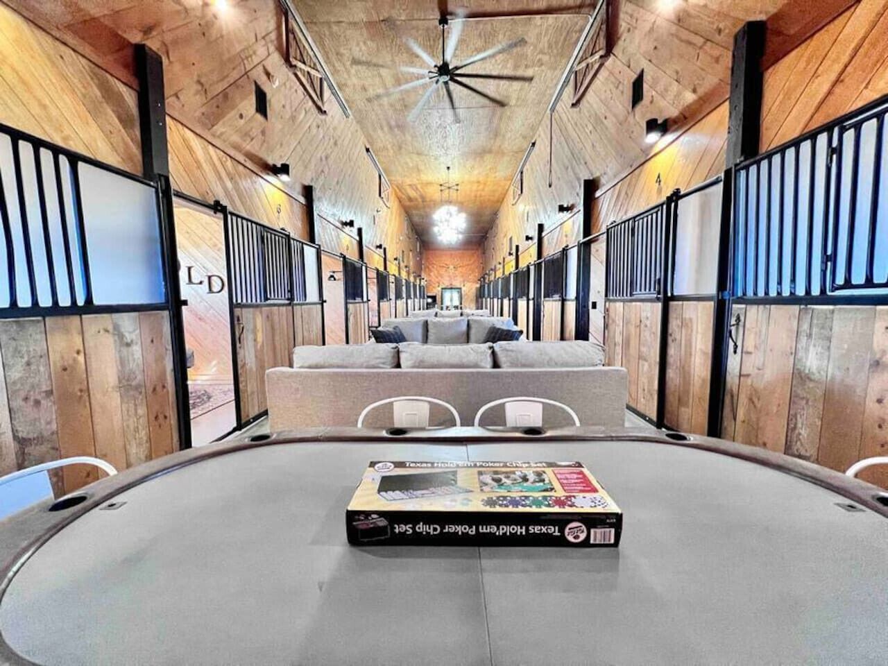 A circular room with a central table displaying a Texas Hold'em Poker Chip Set. The room has wooden walls and a ceiling fan.
