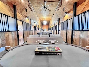 Quarto circular com uma mesa central exibindo um conjunto de fichas de Texas Hold'em. O quarto possui paredes de madeira e um ventilador de teto.
