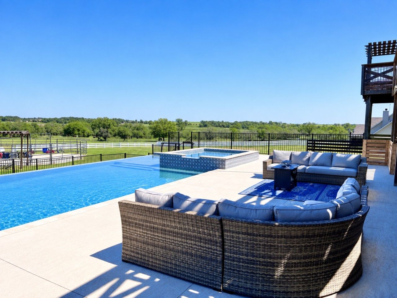 A swimming pool with a wicker sofa and a pergola.