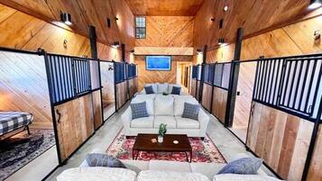 A spacious living area with a sofa set, a coffee table, and a TV mounted on the wall.