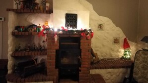 A cozy room with a brick fireplace, a small Christmas tree, and festive decorations.