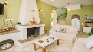 Sala de estar com lareira, sofá, mesa de centro e escada para outro andar.