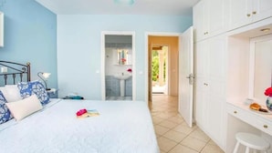 Quarto com cama, mesa de cabeceira e vista para o banheiro.