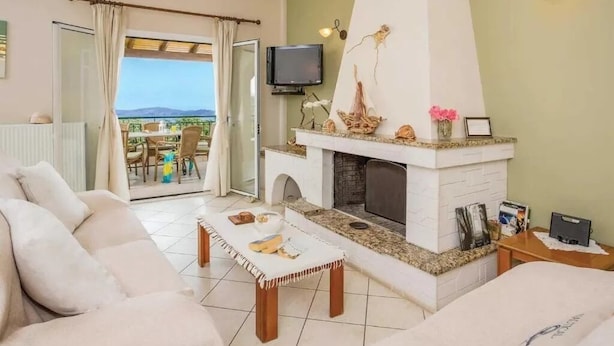 Uma sala de estar com lareira, sofá, mesa de centro e televisão.