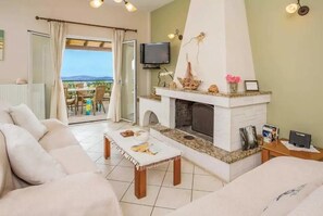 A living room with a fireplace, a sofa, a coffee table, and a television. - Villa Nafsika with amazing view (Corfu)