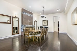 Un coin repas avec une table et des chaises en bois, un mur recouvert de carreaux et un lustre.