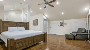 Un dormitorio amplio con una cama de madera, un ventilador de techo y un sofá gris.