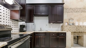Una cocina moderna con armarios de madera oscura, estufa de acero inoxidable y salpicadero de azulejos.