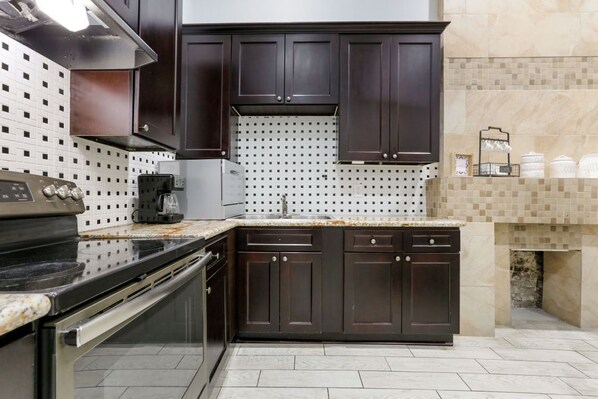 Uma cozinha moderna com armários de madeira escura, fogão de aço inoxidável e painel de azulejos.