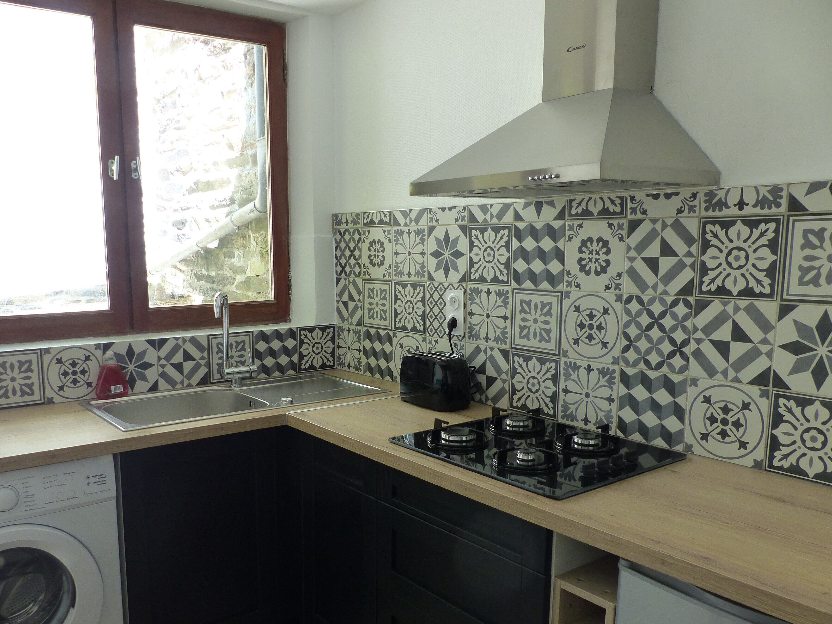 A kitchen with a sink, stove, and a washing machine.