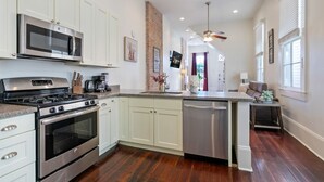 Una cocina moderna con electrodomésticos de acero inoxidable, armarios blancos y una isla central.