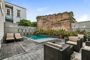 A backyard with a swimming pool, outdoor furniture, and a brick wall. - Spacious 2BR in Prime Garden District Location w/ Pool (New Orleans)
